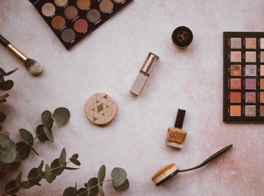 a flatlay of makeup and nail varnish with a sprig of eucalyptus