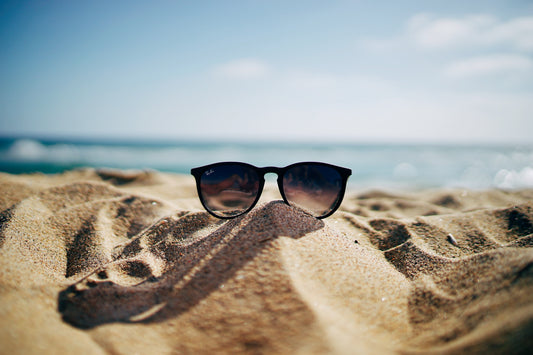 a pair of sunglasses laid in the sand on a beach