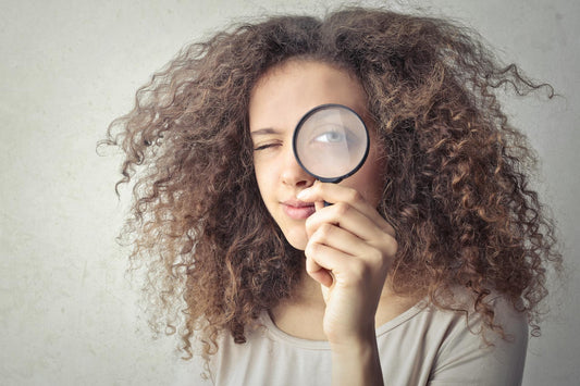 woman looks through magnifying glass