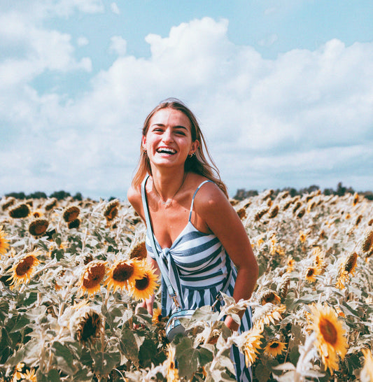 woman in a striped dress smiling in a field of sunflowers