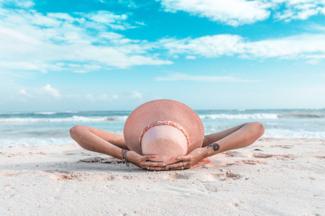 woman wearing a large sunhat laying on the beach