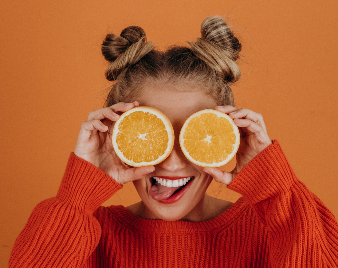 woman holds oranges in front of her eyes